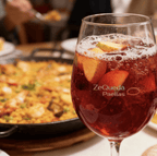 Jarra de sangría frutal de la casa con trozos de manzana y cítricos para acompañar pedidos de paella a domicilio en Bogotá y Sabana Norte.