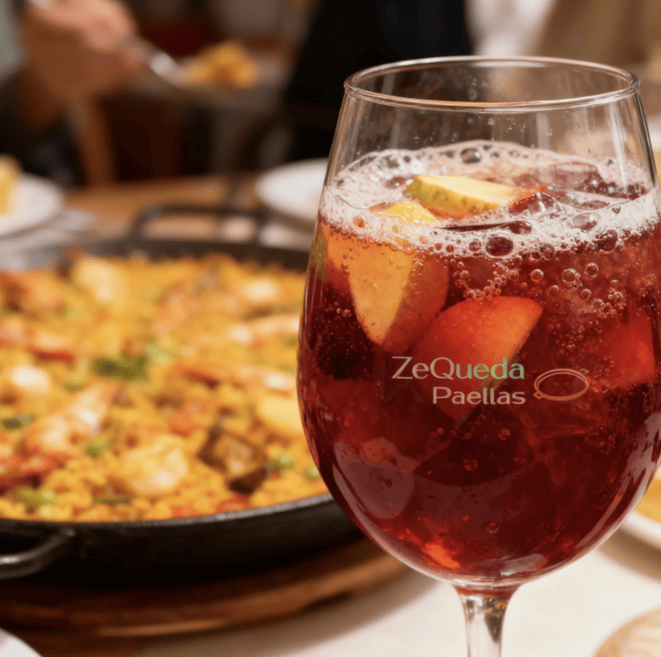 Jarra de sangría frutal de la casa con trozos de manzana y cítricos para acompañar pedidos de paella a domicilio en Bogotá y Sabana Norte.