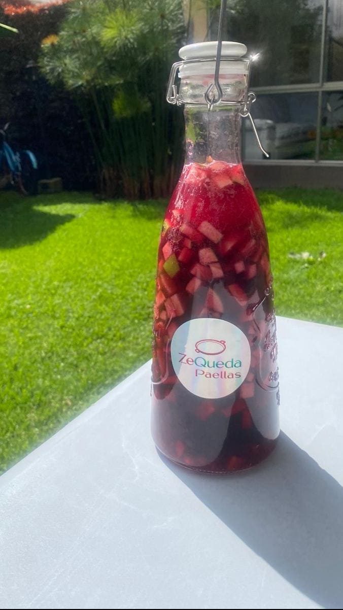 Jarra de un litro de sangría frutal de la casa con trozos de manzana y cítricos para acompañar pedidos de paella a domicilio en Bogotá y Sabana Norte."